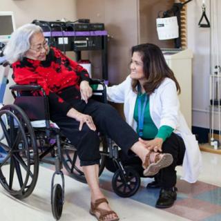A healthcare professional assists an elderly woman in a wheelchair at a clinic.