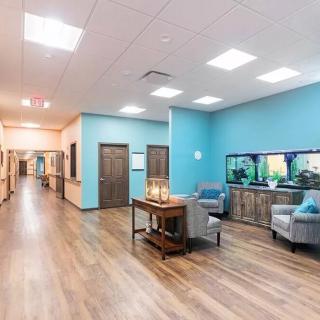 A modern office hallway with a waiting area featuring comfortable seating and an aquarium.