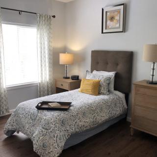 A cozy bedroom with a single bed, decorative pillows, and stylish furnishings.