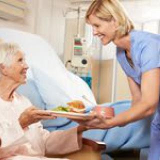A nurse delivering a meal to a patient in a hospital.
