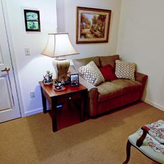 A cozy living room corner with a sofa, table, lamp, and artwork on the wall.