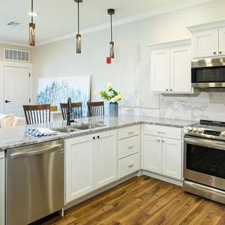 A modern kitchen with white cabinets, stainless steel appliances, and granite countertops.