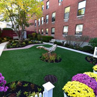 A beautifully landscaped garden with colorful flowers and lush greenery in front of a brick building.