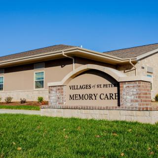 A memory care facility with a prominent sign and well-maintained lawn.