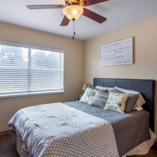 A cozy bedroom with a bed, bedside lamp, and ceiling fan.