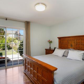 A cozy bedroom with a wooden bed frame and sliding glass doors opening to a garden view.