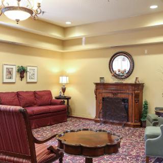 A cozy living room featuring a red sofa, classic fireplace, and decorative elements.