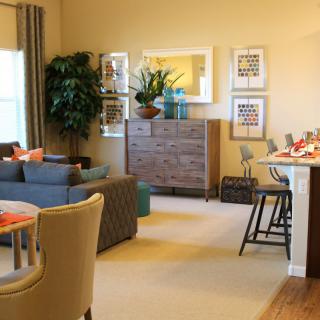 A cozy living room with a sofa and dining area, decorated with plants and artwork.