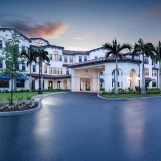 A majestic building with palm trees lining the entrance at sunset.
