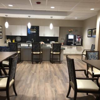 A modern kitchen and seating area with tables, chairs, and pendant lighting.