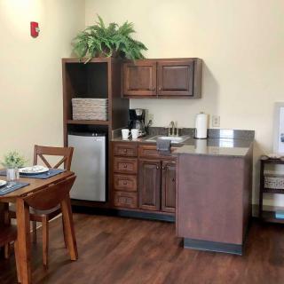 A cozy kitchenette with wooden cabinets, a mini fridge, and a small dining area.