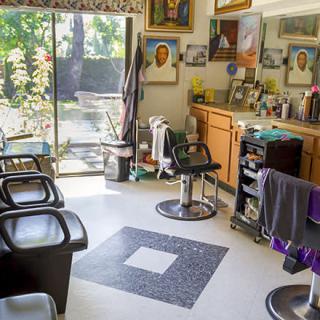 A bright and welcoming barbershop interior with chairs, mirrors, and various hair styling equipment.