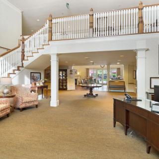 A spacious and bright living area featuring a staircase, comfortable seating, and an office desk.