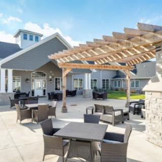 A spacious outdoor patio area with modern furniture and a wooden pergola.