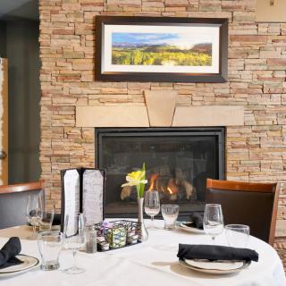 A cozy restaurant setting featuring a neatly arranged dining table in front of a warm fireplace.