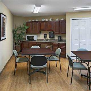 A cozy office break room with tables, chairs, and a kitchenette.