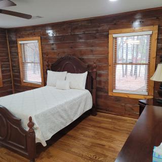 A cozy bedroom in a log cabin with wooden walls and a double bed.