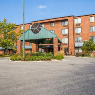 The image shows the exterior of a hotel with a landscaped entrance area.