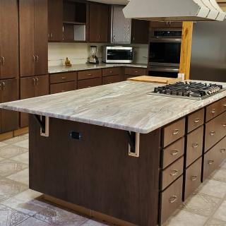 A modern kitchen with a central island featuring a stove and ample cabinetry.