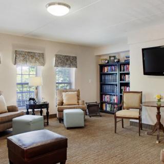 A cozy living room with comfortable seating, a television on the wall, and a bookshelf filled with books.
