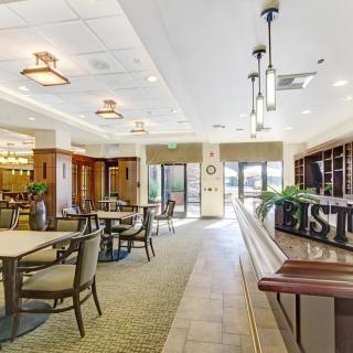 A modern restaurant interior with neatly arranged tables and chairs, featuring warm lighting.