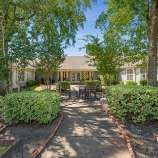 A charming house with a well-maintained garden and outdoor seating, surrounded by lush trees and greenery.