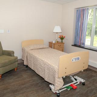 A hospital room with a single bed and basic furniture.