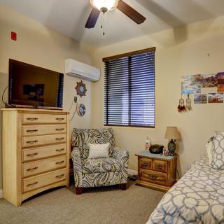 Cozy bedroom with a chest of drawers, armchair, and bed under soft lighting.