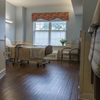 A clean and well-organized hospital room with a bed, chairs, and a window.