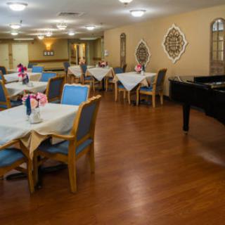 A cozy dining area featuring elegantly set tables and a grand piano.