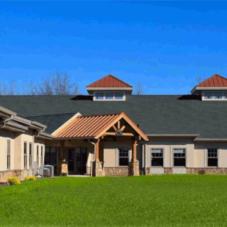 A modern building with a pitched roof and a landscaped lawn under a clear blue sky.