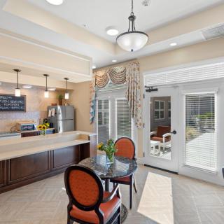 A cozy cafe interior with a counter and seating area, featuring elegant lighting and large windows.