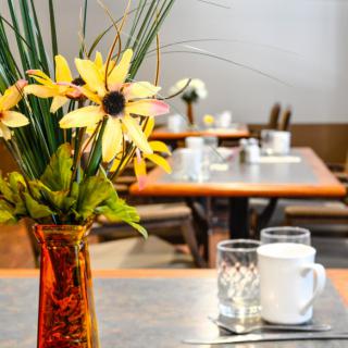 A beautifully set dining table with a vase of flowers.
