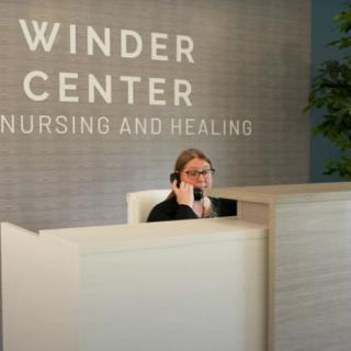 A receptionist at the Winder Center for Nursing and Healing sits behind a desk, speaking on the phone.
