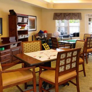 A cozy dining room with a wooden table, chairs, and shelves in a warmly lit space.