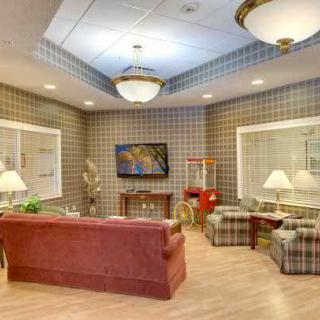 A cozy lounge area with couches, a television, and a popcorn machine, set against checkered wallpaper.