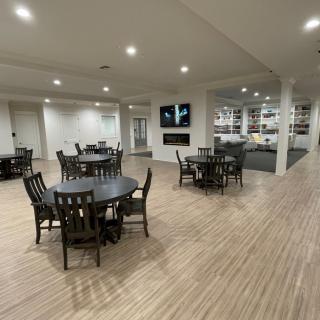 A modern interior space featuring neatly arranged tables and chairs with ample lighting.