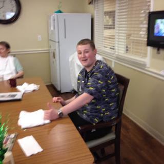 A cheerful gathering at a dining table, with one person smiling for the camera.