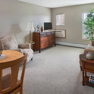 A cozy living room with various pieces of furniture, including a television, chairs, and an indoor plant.