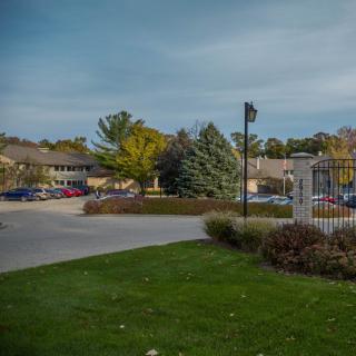 A suburban parking lot surrounded by trees and buildings under a cloudy sky.