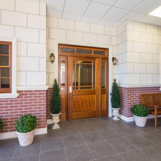 A well-designed entrance with a wooden door and potted plants against a brick wall.