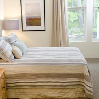 A bright and cozy bedroom with striped bedding and soft lighting.