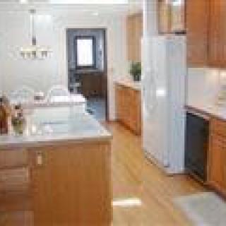 A modern kitchen with wooden cabinets and a central island, featuring bright lighting and spacious design.