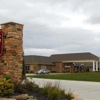 A brick sign and entrance to a large building complex under a cloudy sky.