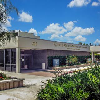 A modern building under a partly cloudy sky with landscaped surroundings.