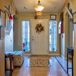 A cozy entryway featuring a front door adorned with a wreath, flanked by windows and warm lighting.