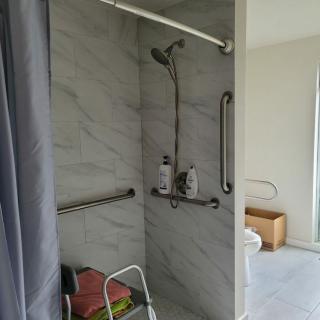 An accessible shower equipped with grab bars and a shower chair.