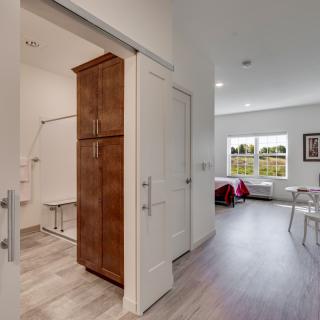 A modern apartment interior featuring an open living area with a view into the kitchen and bathroom.