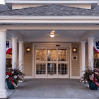The entrance of a building with columns, decorated with plants and flags.