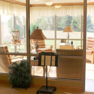 A cozy living room with large windows, wicker furniture, and warm lighting.